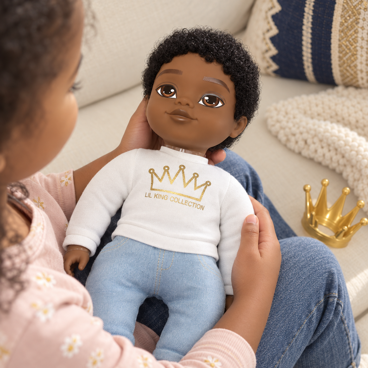 Escena de juego con Littlelistas Louie sobre el regazo, con sudadera blanca y pantalón azul.